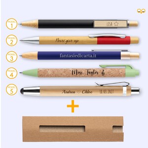 Puede incluir: Cinco bolígrafos con diferentes diseños y una caja de cartón. Los bolígrafos incluyen barriles negros, plateados, azules, verdes y color bambú. Algunos bolígrafos tienen texto que dice "LISA", "Never give up", "fantasiedicarta.it", "Miss Taylor", "Andrea Chloe 18.03.2027".