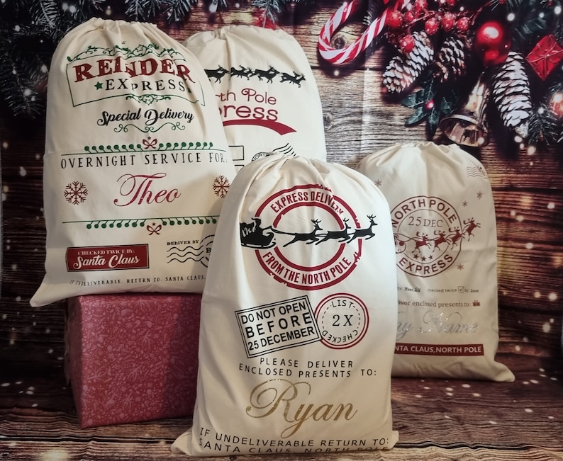 May include: Three white canvas Santa sacks with red and green designs. The sacks are decorated with reindeer, sleighs, and the words "Express Delivery", "North Pole Express", and "Do Not Open Before 25 December". The sacks are personalized with the names "Theo", "Ryan", and "My Name".