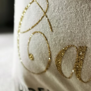 May include: White fabric with the word "Save" written in gold glitter.