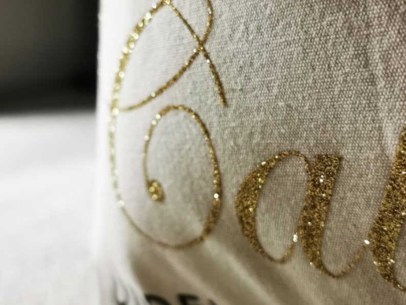 May include: White fabric with the word "Save" written in gold glitter.