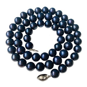 May include: A necklace composed of numerous dark blue pearls. The pearls are strung together, forming a circular shape. The necklace has a silver-colored clasp. The pearls have a lustrous sheen, reflecting light.
