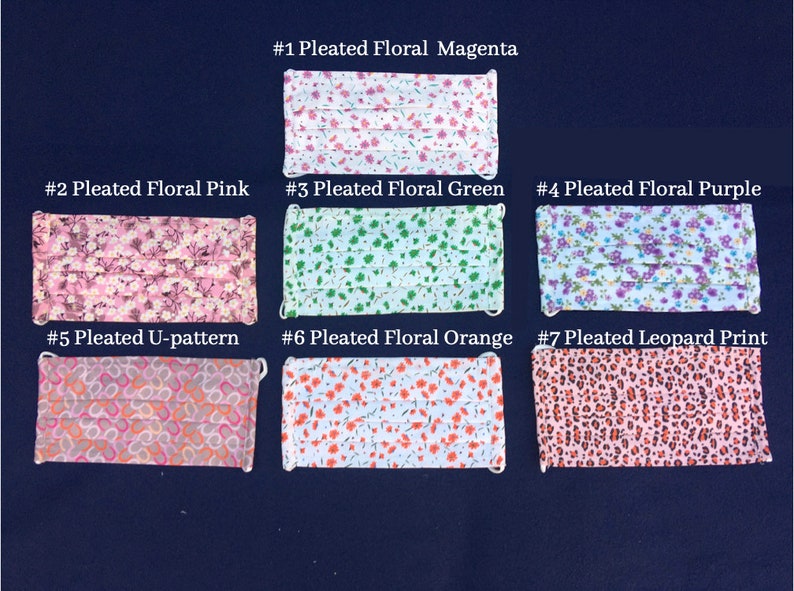 May include: Seven pleated face masks with various floral and patterned designs are displayed on a dark blue surface. The masks include floral patterns in magenta, pink, green, purple, and orange, along with a U-pattern and leopard print.