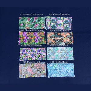 May include: A collection of eight pleated face masks with various floral and paisley patterns. Each mask has white elastic ear loops. The masks are labeled with numbers and names, including "Pleated Hawaiian," "Pleated Hibiscus," and "Pleated Blue."