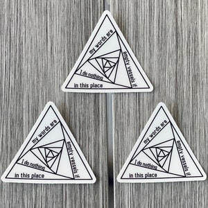 Pode incluir: Três adesivos triangulares brancos com texto preto e um design geométrico. O texto nos adesivos diz "minhas palavras são vasos vazios se eu não fizer nada neste lugar".