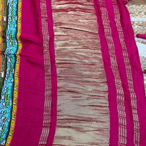 May include: A pink fabric with a gold border. The fabric has a textured pattern and is folded in half.