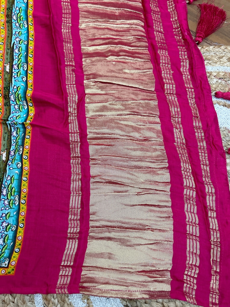 May include: A pink fabric with a gold border. The fabric has a textured pattern and is folded in half.