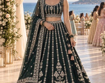 May include: A dark green lehenga set featuring a sleeveless blouse and a floor-length skirt, both adorned with intricate white floral embroidery. The ensemble includes a matching sheer dupatta with a wide embroidered border and decorative tassels.