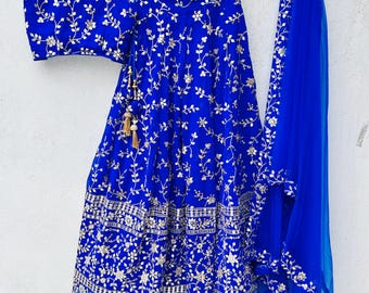 Può includere: Un abito da sposa indiano in tre pezzi di colore blu reale con ricami e paillettes argentate. L'abito comprende un top corto, una gonna e una dupatta trasparente.