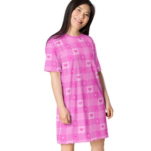 May include: A pink and white plaid dress with pink hearts. The dress has short sleeves and a relaxed fit.
