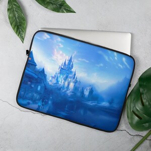 Puede incluir: Una funda para portátil azul con una ilustración de fantasía de un castillo cubierto de nieve y un pueblo en primer plano. El castillo está iluminado por una suave luz blanca, y el cielo es de un azul pálido con nubes tenues.