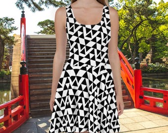 Puede incluir: Un vestido skater sin mangas blanco y negro con un patrón geométrico de triángulos. El vestido está fotografiado frente a un puente rojo.