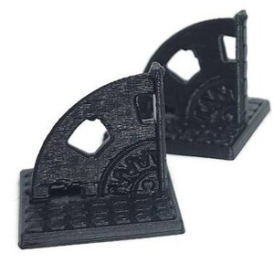 May include: Four black plastic corner pieces with a decorative design. Each piece has a square base and a curved top with a cutout design.