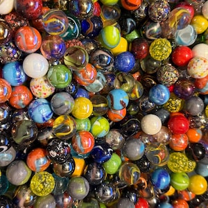 May include: A collection of colorful glass marbles in various sizes and designs. The marbles feature a mix of colors, including red, blue, green, yellow, and orange, with swirling patterns and solid hues. Some have a glossy finish.