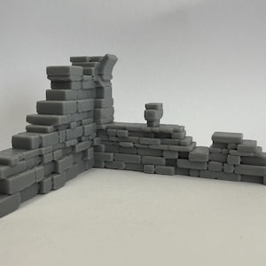 May include: A gray, miniature stone wall section with steps and a corner. The model appears to be made of individual rectangular blocks, creating a textured surface. The design suggests a historical or fantasy theme, suitable for tabletop gaming or model building.