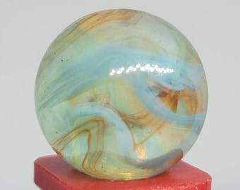 May include: A blue and brown swirl glass marble. The marble has a translucent appearance with swirls of blue and brown glass.