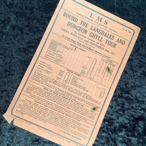 May include: Vintage travel itinerary for the London Midland and Scottish Railway's Dungeon Ghyll Tour, dated September 24th, 1927. The tan paper document features black text detailing routes, times, and fares for train, steam yacht, and coach travel.