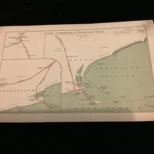 Könnte beinhalten: Eine antike Karte von Dover, Folkestone und Tunbridge Wells, England. Die Karte ist auf cremefarbenem Papier gedruckt mit braunen und roten Linien, die Straßen und Eisenbahnen anzeigen. Die Karte zeigt die Küste, den Ärmelkanal und die Stadt Dover.