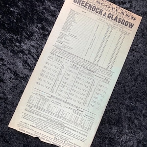 Puede incluir: Un documento antiguo de la Great Central Railway, con horarios y tarifas para Greenock & Glasgow. El papel amarillento se encuentra sobre un fondo negro.