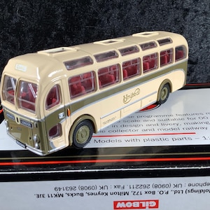 May include: A beige and olive green model bus with the word "United" on the side. The bus has red interior seating and clear windows. The model is a 1:76 scale replica.