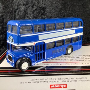 May include: A blue double-decker bus model with white horizontal stripes and the text MIDLAND on the side. The front destination sign displays 560 COWIE. The bus features black wheels, clear windows, and is presented on a 1:76 scale box.