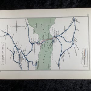 Op de afbeelding: Een vintage kaart van de Forth Bridge, met een gedetailleerde illustratie van de spoorlijnen en de omgeving. De kaart gebruikt blauwe lijnen voor de spoorweg en rood voor de brug, met plaatsnamen in het zwart.