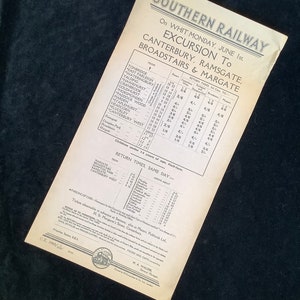 Pode incluir: Um horário de excursão vintage da Southern Railway para o Dia de Pentecostes, 1º de junho de 1921. O horário lista os horários de partida e as tarifas de retorno de várias estações para Canterbury, Ramsgate, Broadstairs e Margate.