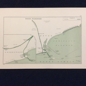Könnte beinhalten: Eine Vintage-Karte von Dover und Folkestone, England, mit grünen Linien, die die Eisenbahnlinien zeigen, und einem grün schattierten Bereich, der den Admiralitätshafen zeigt. Die Karte enthält den Text "Dover Folkestone" und "Admiralty Harbour".