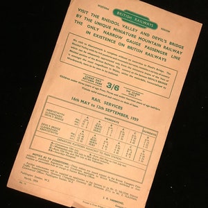 May include: A vintage British Railways poster advertising a scenic train ride through the Rheidol Valley and Devil's Bridge in Wales. The poster features a green and white color scheme with a detailed schedule of train departures and arrivals. The poster includes the text "Visit the Rheidol Valley and Devil's Bridge by the unique miniature mountain railway. The only narrow gauge passenger line in existence on British Railways."