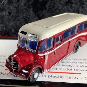 Puede incluir: Un modelo de autobús vintage rojo y crema con ventanas azules. El modelo tiene la palabra "MOUTH" sobre el parabrisas delantero y el número "SB604" en el lateral. El modelo es un vehículo fundido a presión a escala 1:76.