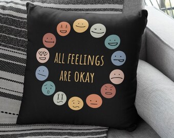 May include: Black throw pillow with a circle of colorful emoji faces and the text "ALL FEELINGS ARE OKAY".