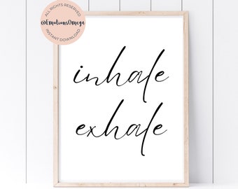 May include: A white framed print with black calligraphy that reads "inhale exhale".