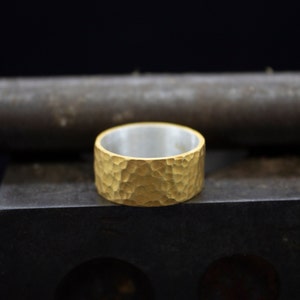 Puede incluir: Un anillo de banda de oro con textura martillada. El anillo es ancho y tiene un interior plateado.
