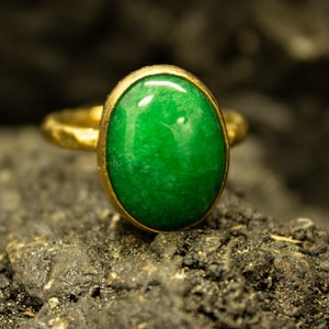 May include: A gold ring with a large, oval-shaped green gemstone.