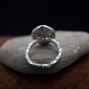 May include: A silver ring with a textured band and a round, hammered silver top.