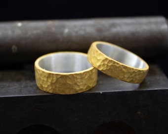 May include: Two gold rings with a hammered texture. The rings are stacked on top of each other.