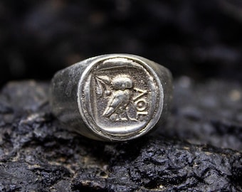 May include: A silver ring with a raised design of a bird and the letters "AOL" on the top.