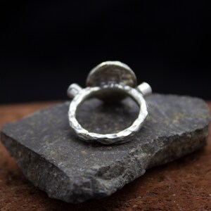 May include: A silver ring with a textured band and a round, hammered silver top.