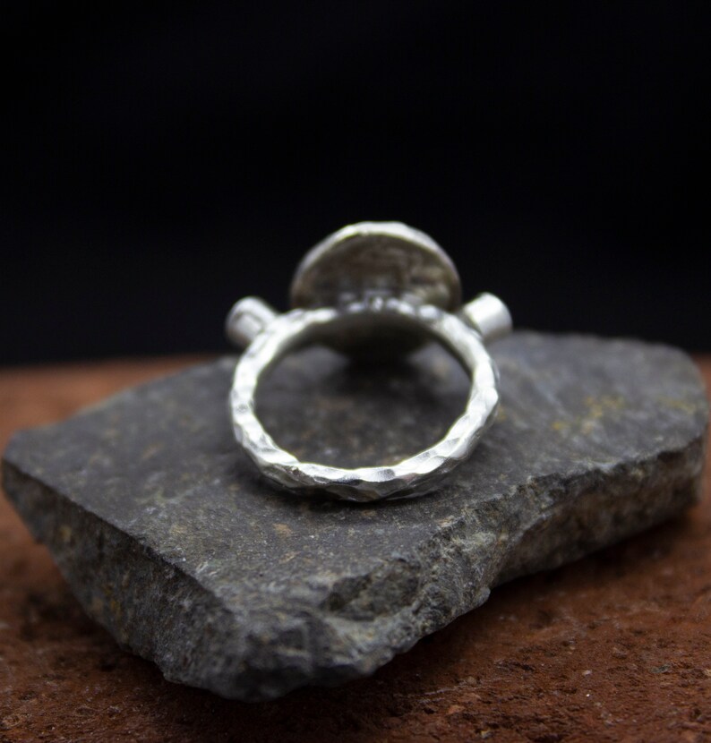 May include: A silver ring with a textured band and a round, hammered silver top.