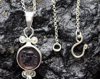 May include: A silver necklace with a pendant featuring a dark brown cameo of an owl. The pendant is surrounded by silver beads and has a silver chain attached.