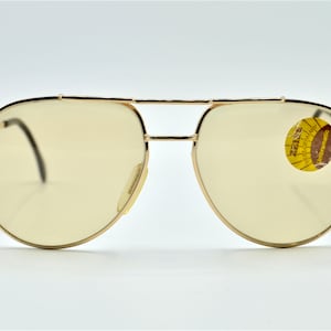 May include: Gold aviator sunglasses with clear lenses and a Zeiss West-Germany Unibromatic label on the right lens.