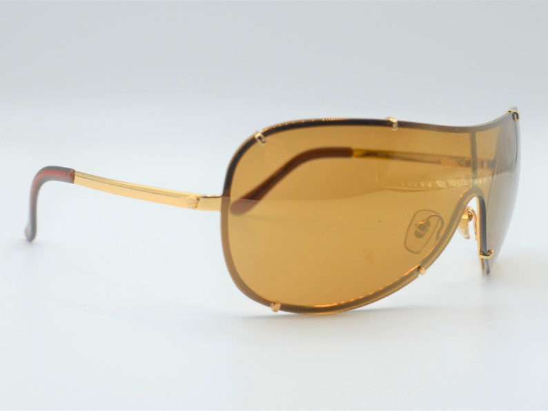 May include: Gold-tone aviator sunglasses with brown lenses and a curved frame.