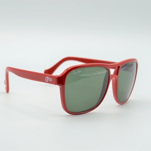May include: Red Ray-Ban sunglasses with green lenses. The sunglasses have a white "Cats" logo on the side.