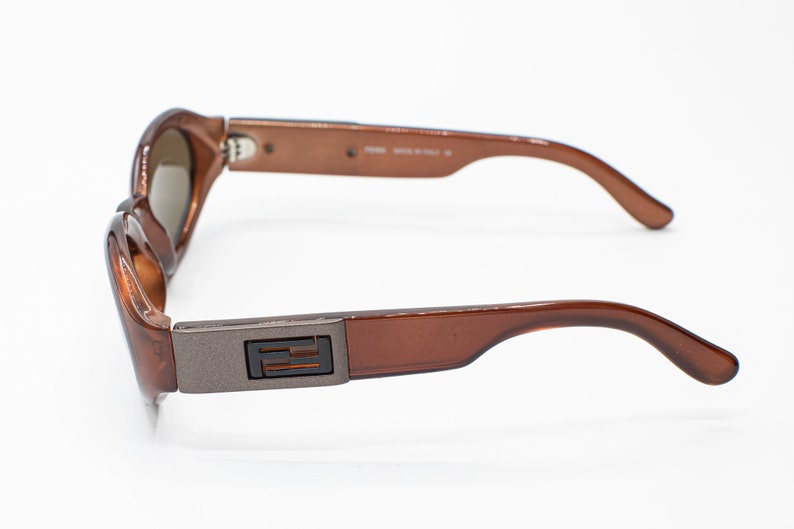 May include: Brown plastic sunglasses with a silver metal accent on the side featuring the letter "F".
