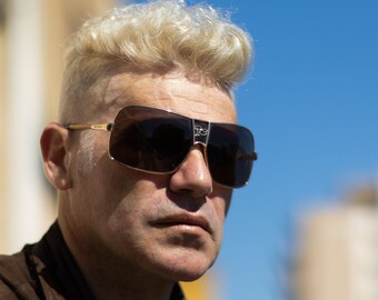 Puede incluir: Un hombre con el pelo corto, rubio y rizado que lleva gafas de sol oscuras con montura dorada.