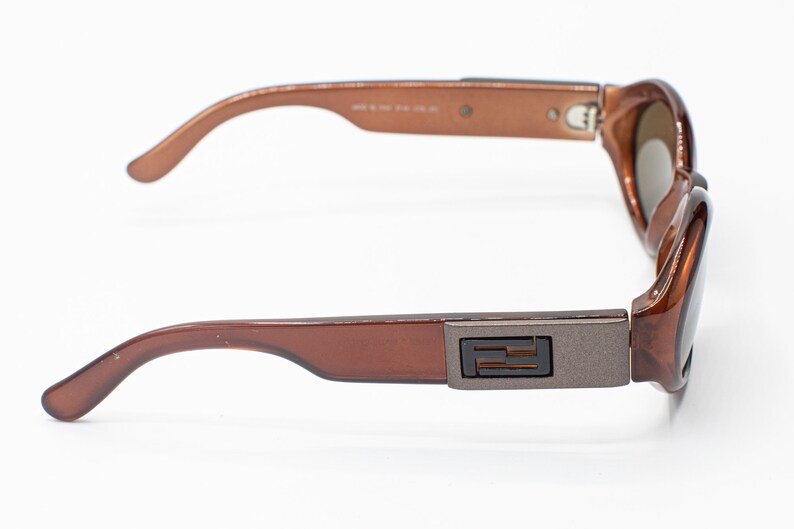 May include: Brown plastic sunglasses with a silver metal accent on the side featuring the letter "F".
