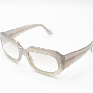 May include: A pair of light gray rectangular-shaped eyeglasses with clear lenses.