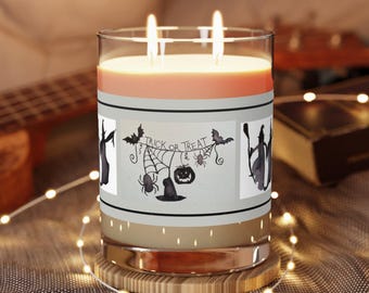 May include: A glass candle jar with a light pink candle inside. The jar has a label with a black and white illustration of a witch, bats, a spider, a pumpkin, and the text "Trick or Treat".