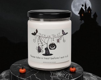 May include: A white candle in a clear glass jar with a black lid. The label features a black ink illustration of spiderwebs, bats, a spider, a pumpkin, and a witch hat with the text "TRICK OR TREAT" and "Please take a treat before I eat it all."