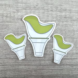 Puede incluir: Tres portavelas de cerámica en forma de pájaro de diferentes tamaños, de color verde y blanco. Los portavelas son de cerámica blanca con un diseño de pájaro verde en la parte superior.