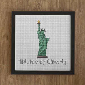 Peut inclure: Une broderie encadrée représentant la Statue de la Liberté en vert et jaune avec le texte "Statue of Liberty" en dessous.